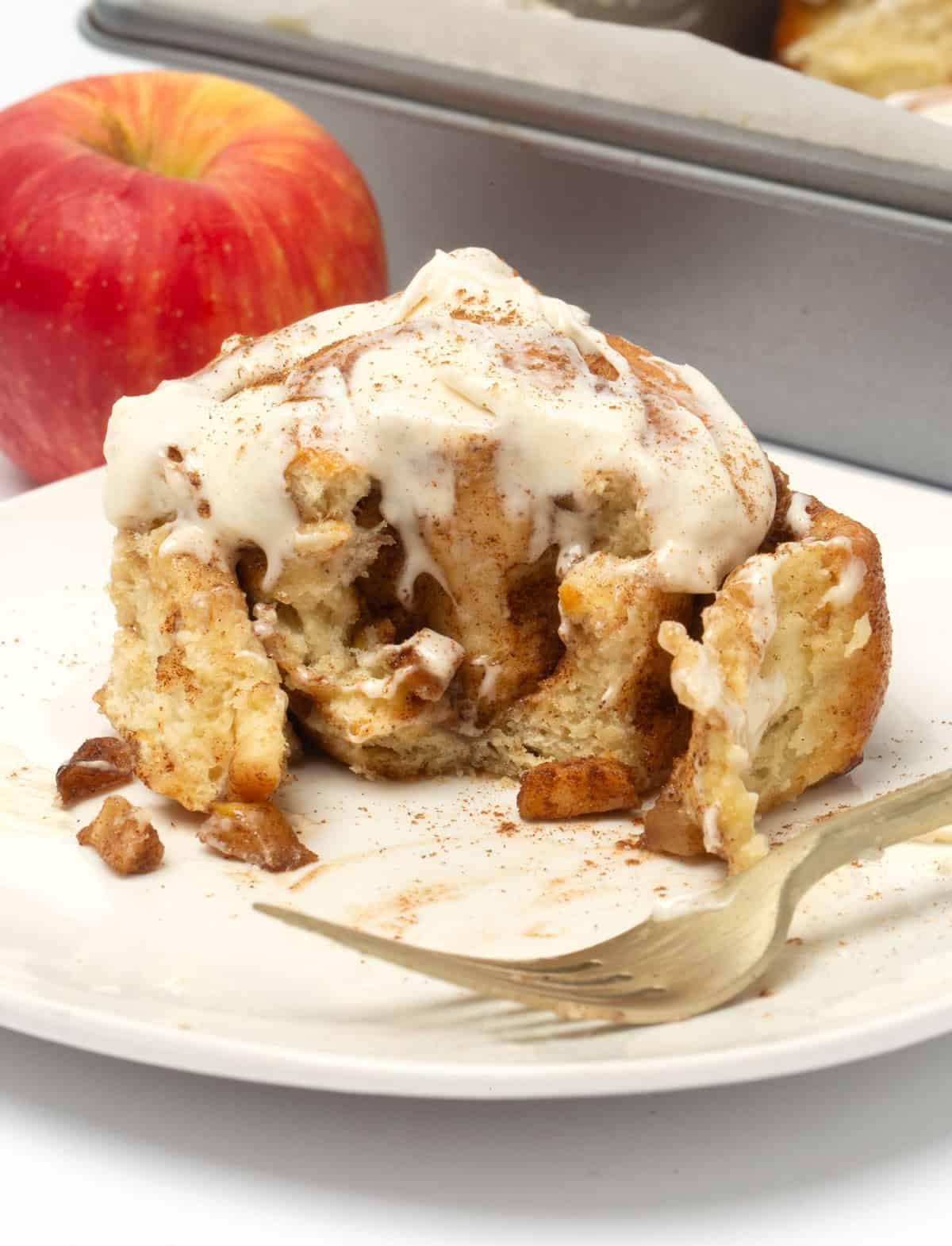 white plate with apple cinnamon rolls and apple in background