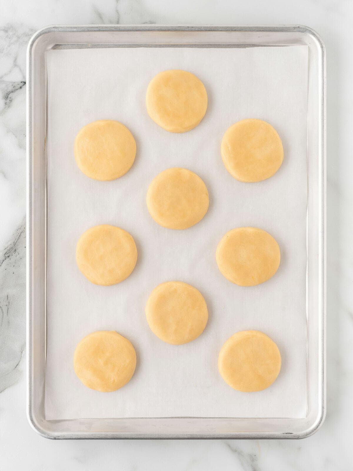 baked frosted sugar cookies on parchment lined baking sheet