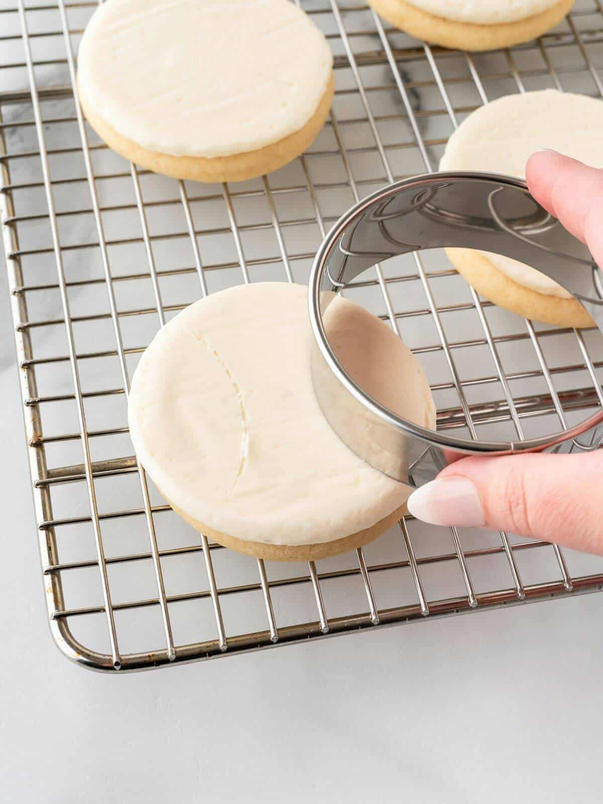 using a cookie cutter to make lines on frosted sugar cookie