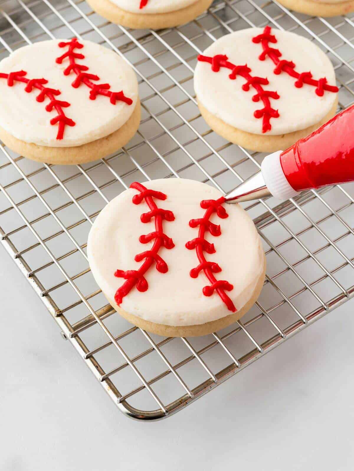 piping red icing on baseball sugar cookie