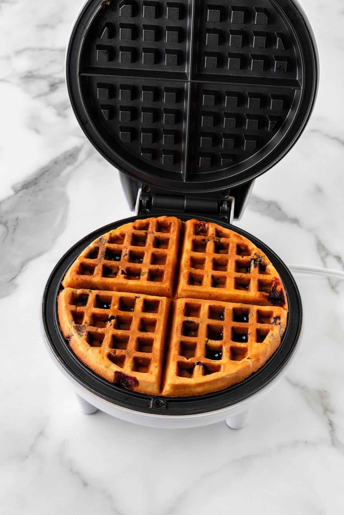 Blueberry waffle in waffle iron.