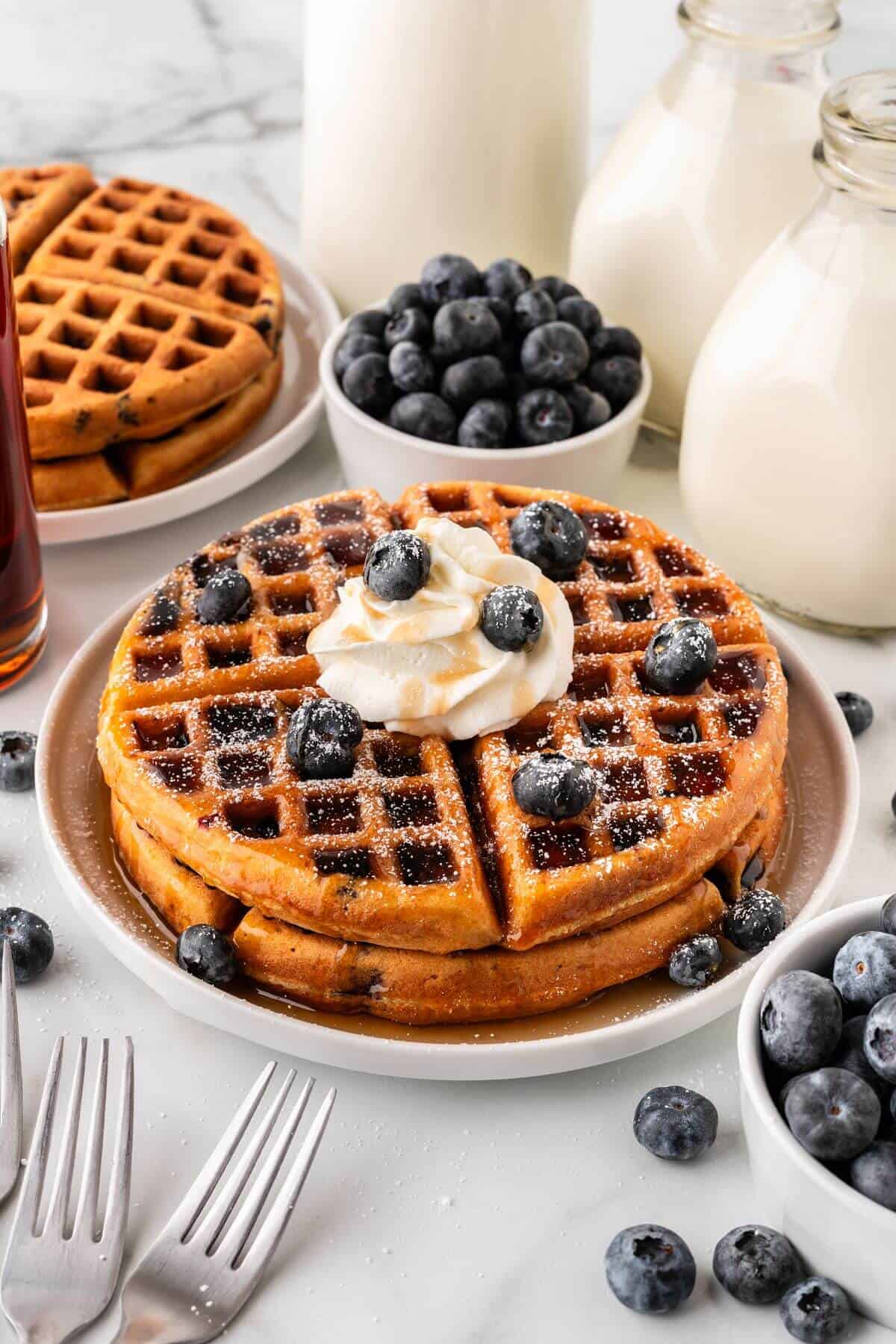 Blueberry waffles with whipped cream and blueberries on top.