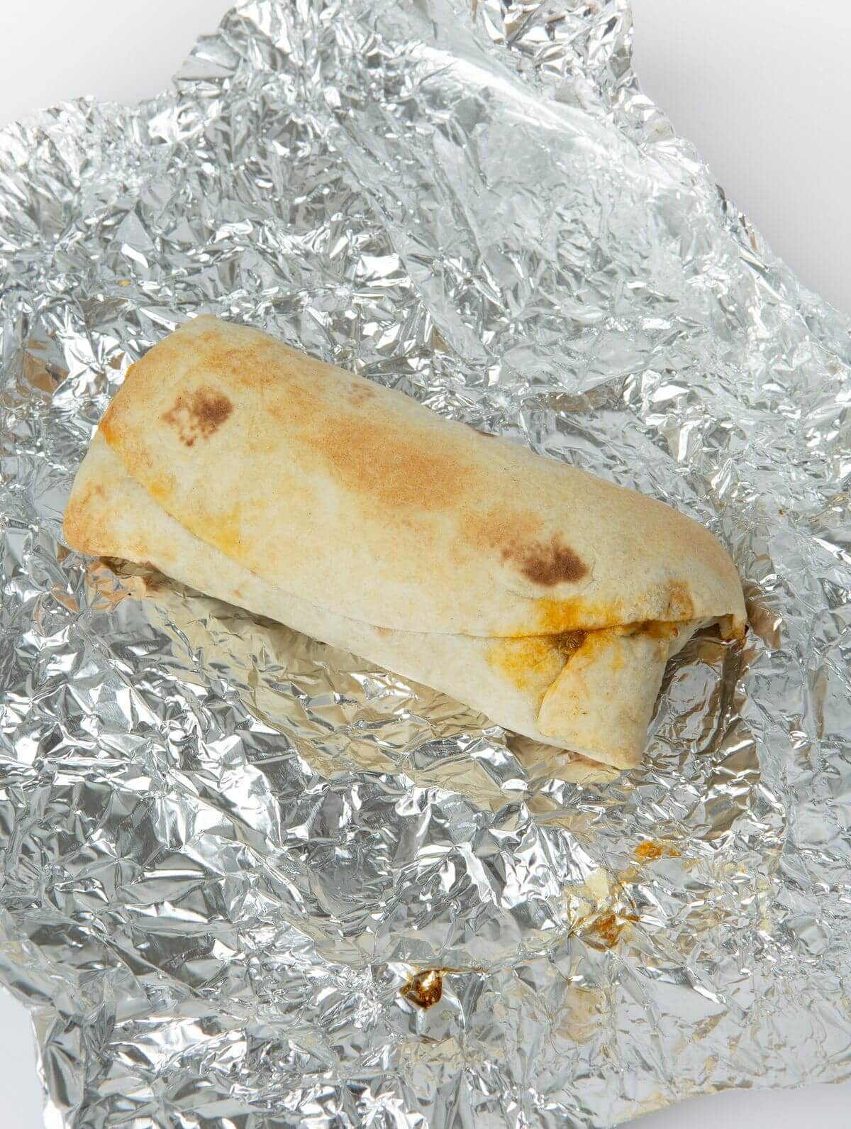 baked breakfast burrito on piece of tin foil
