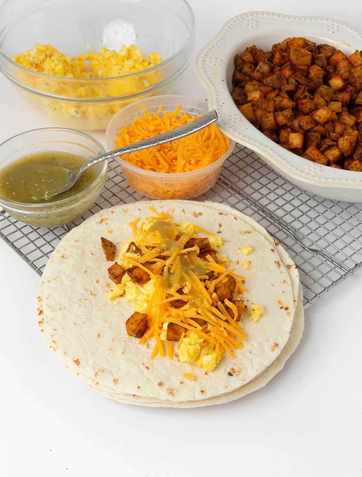 flour tortilla with egg, cheese, potatoes and salsa in the middle