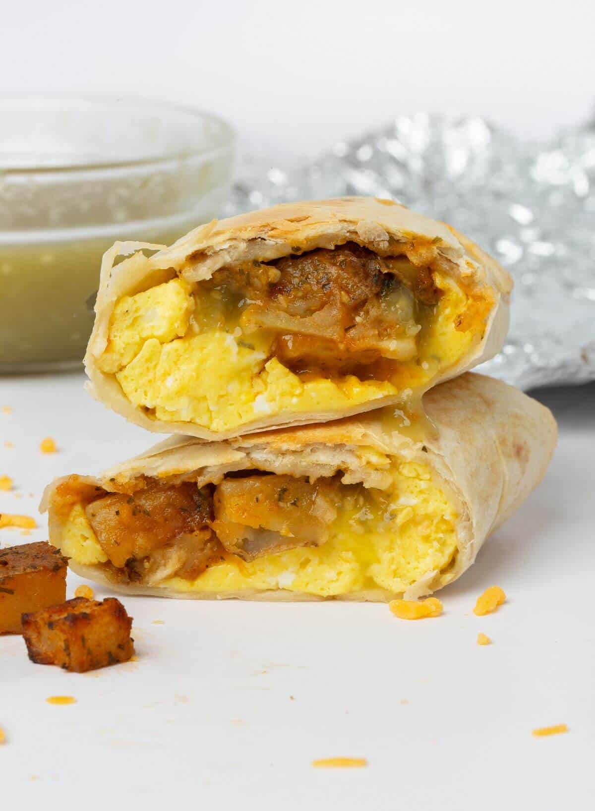 breakfast burrito cut in half on cutting board