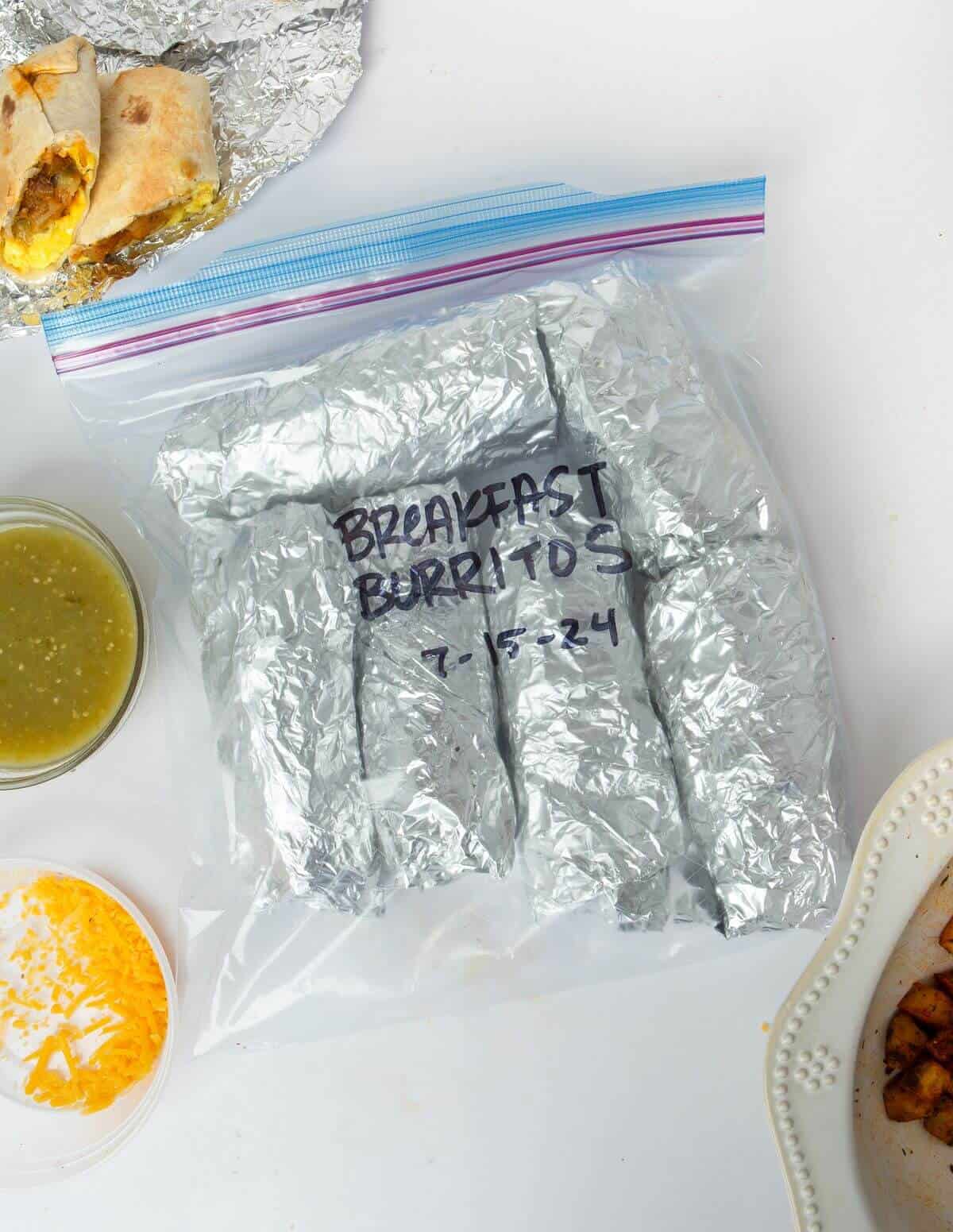 frozen meal prep burritos wrapped in tin foil in freezer bag