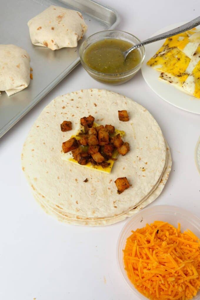 tortillas with egg and potatoes placed in the middle to fill breakfast crunchwrap