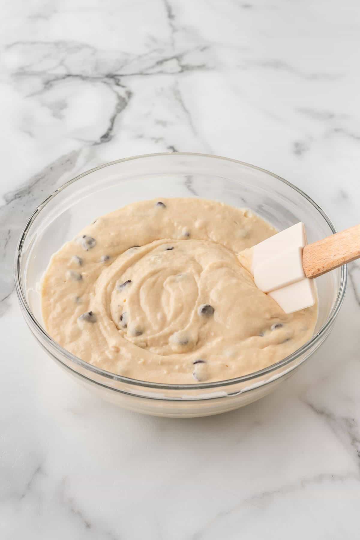Chocolate chip waffle batter in mixing bowl with spatula.