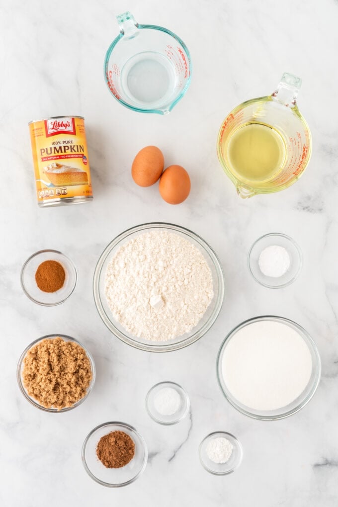 Glass bowls with various ingredients sitting on a white and gray marble countertop. 