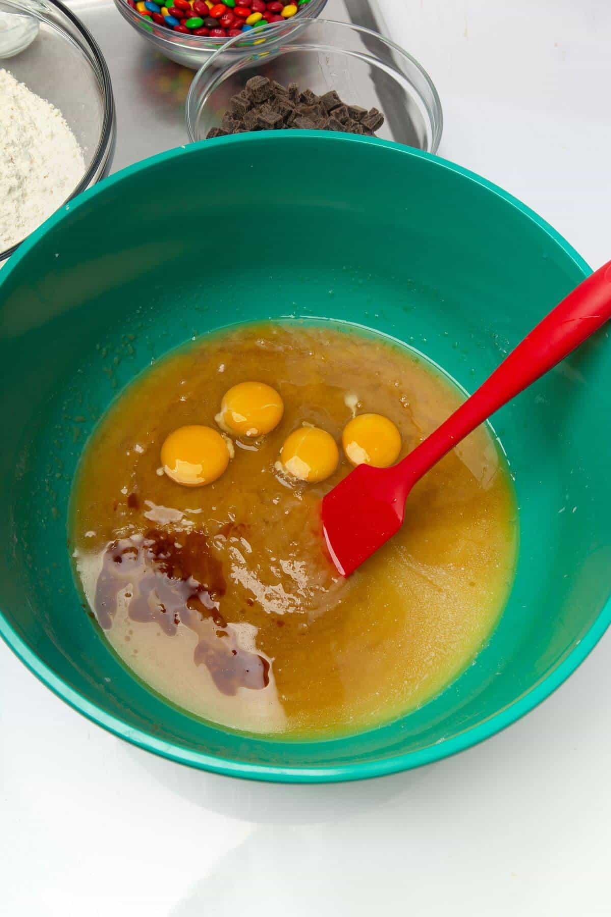 Wet ingredients for freezer cookie dough in green. mixing bowl with spatula.