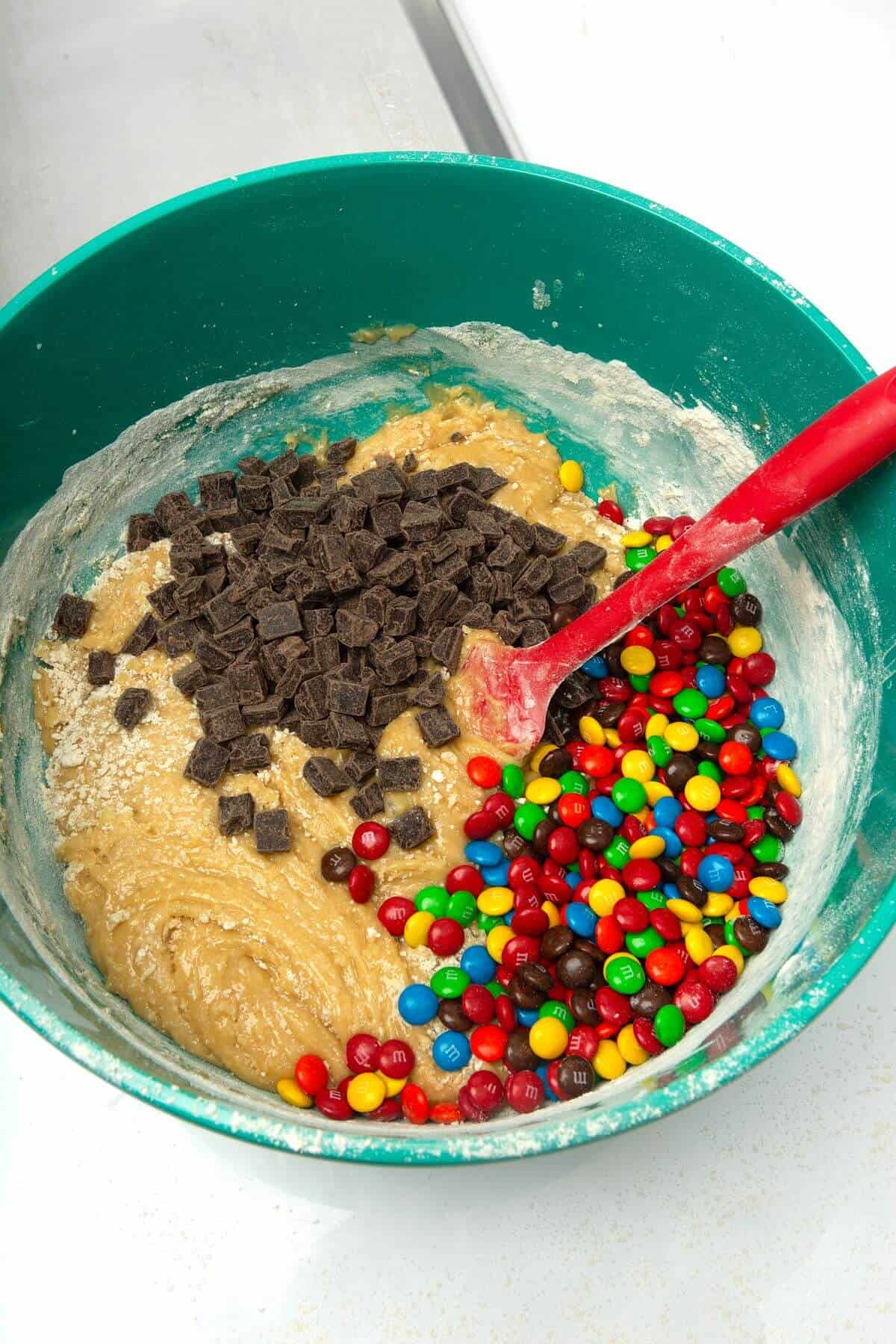 Mix-ins added to dough in mixing bowl with spatula for freezer cookie dough.
