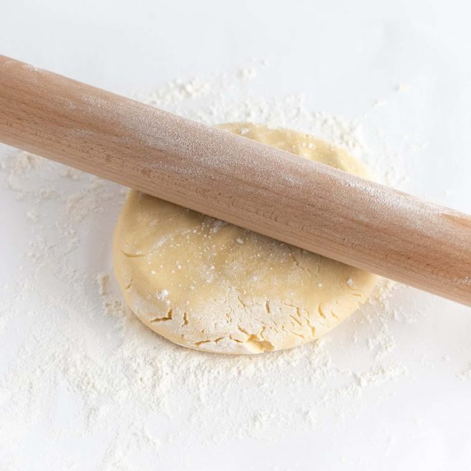Wooden rolling pin rolling out sugar cookie dough