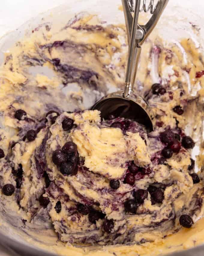 Bowl of mixed blueberry muffin batter with cookie scoop.