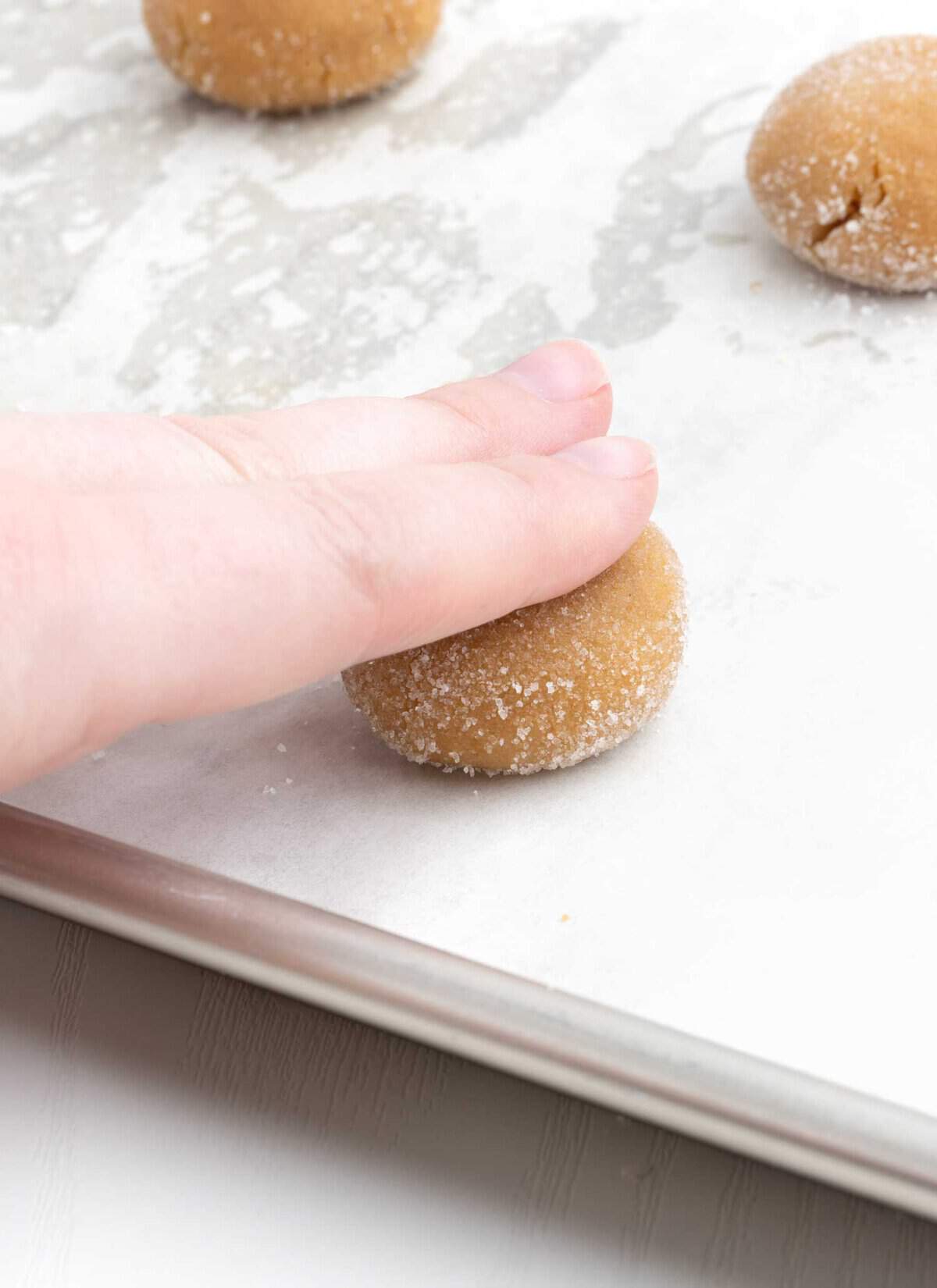 hand pressing down on peanut butter cookie dough ball