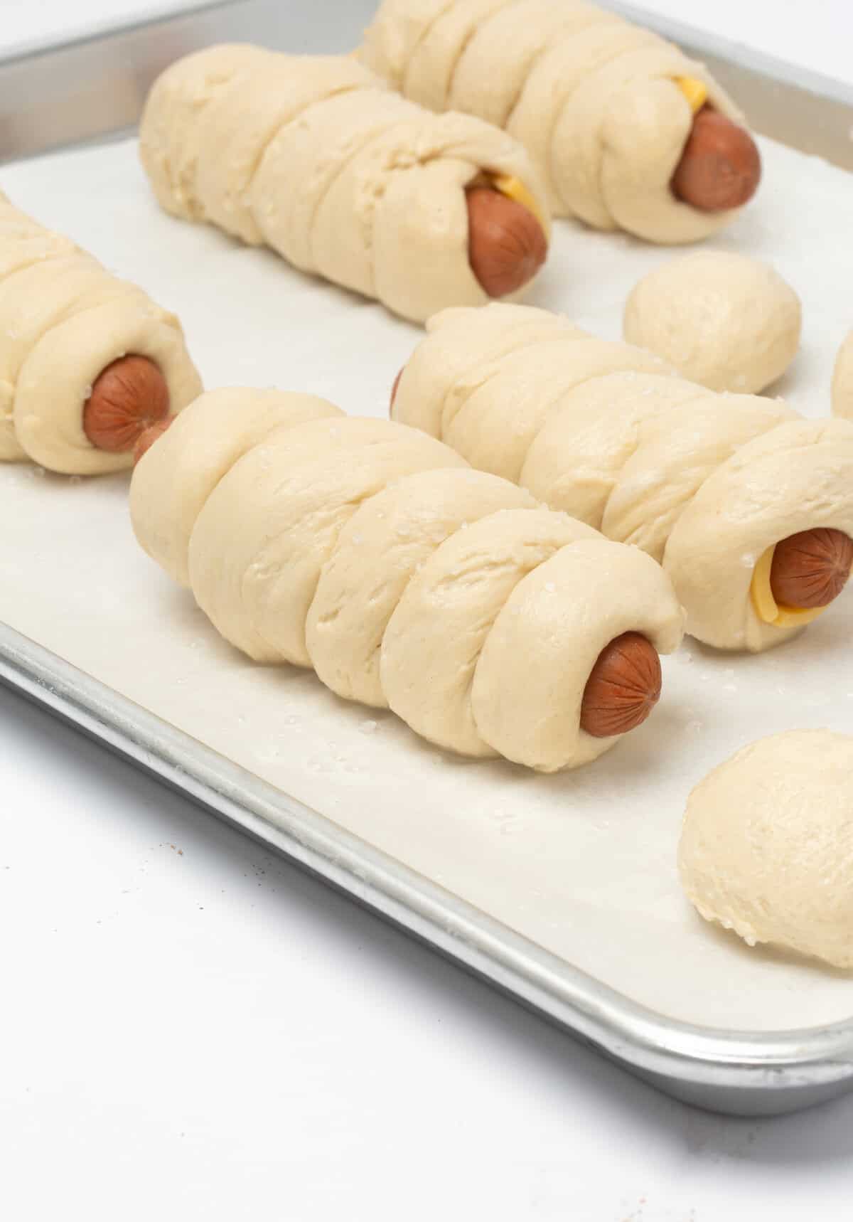Unbaked soft pretzel dough wrapped around hotdog.