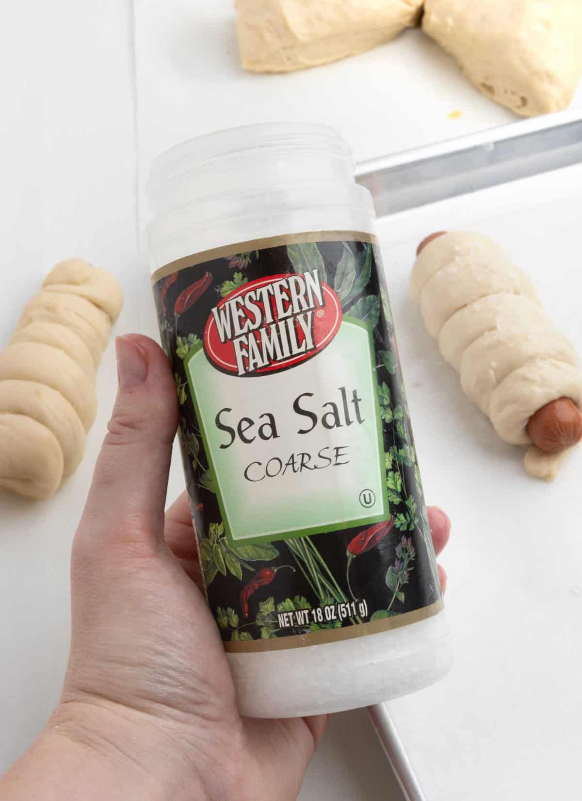 hand holding bottle of coarse sea salt