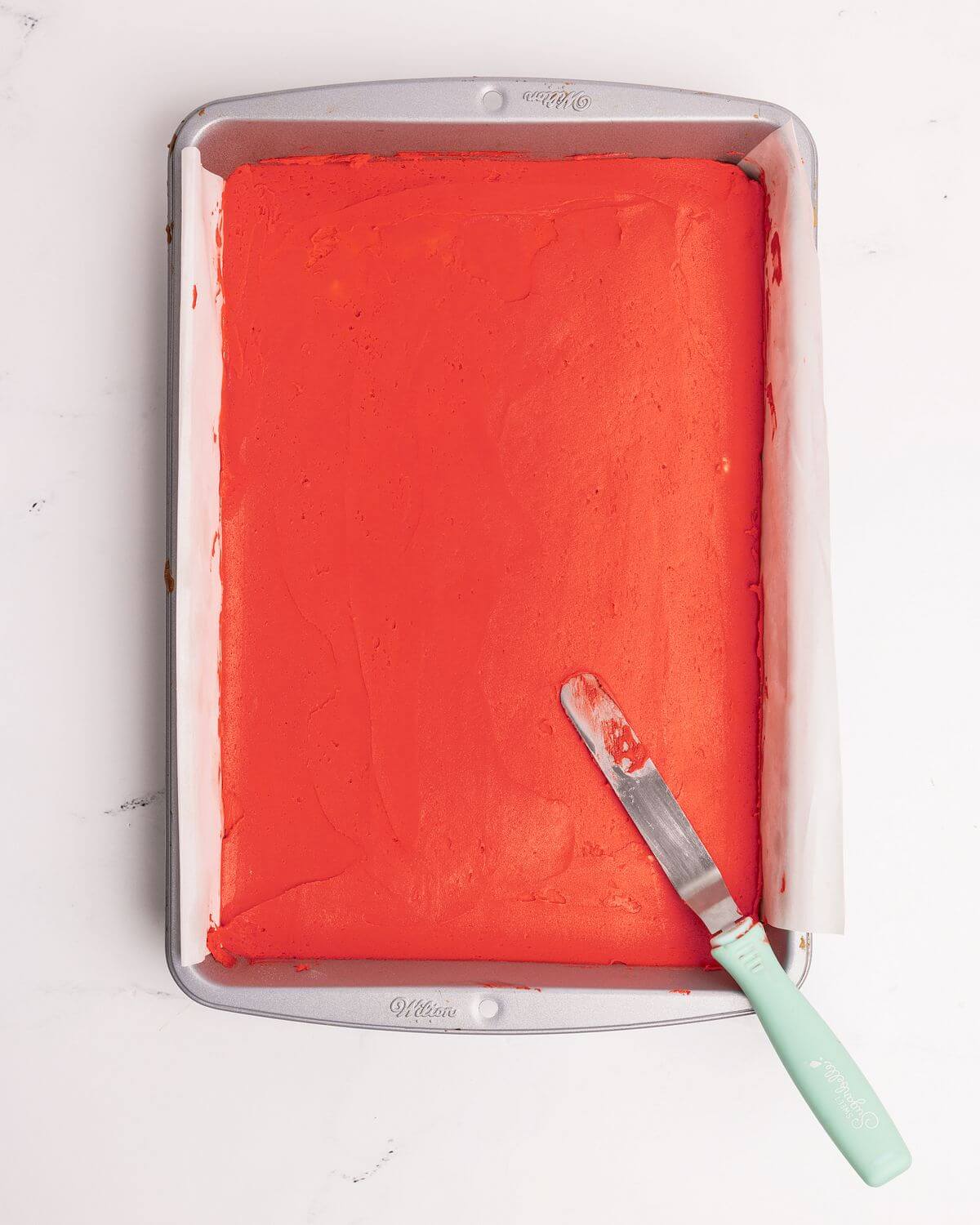 red frosting spread over sugar cookie bar