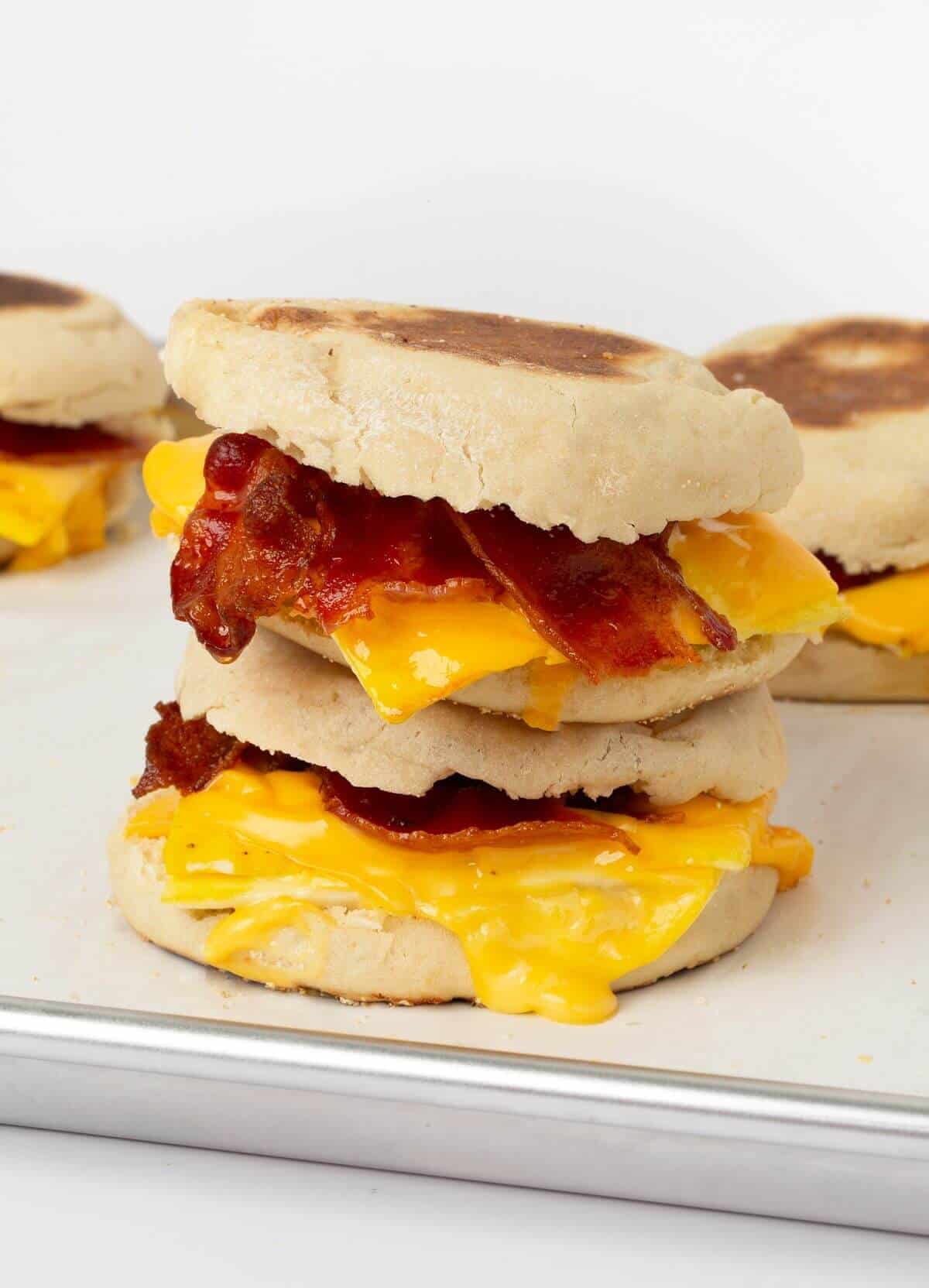 two breakfast sandwiches stacked on top of each other on baking sheet