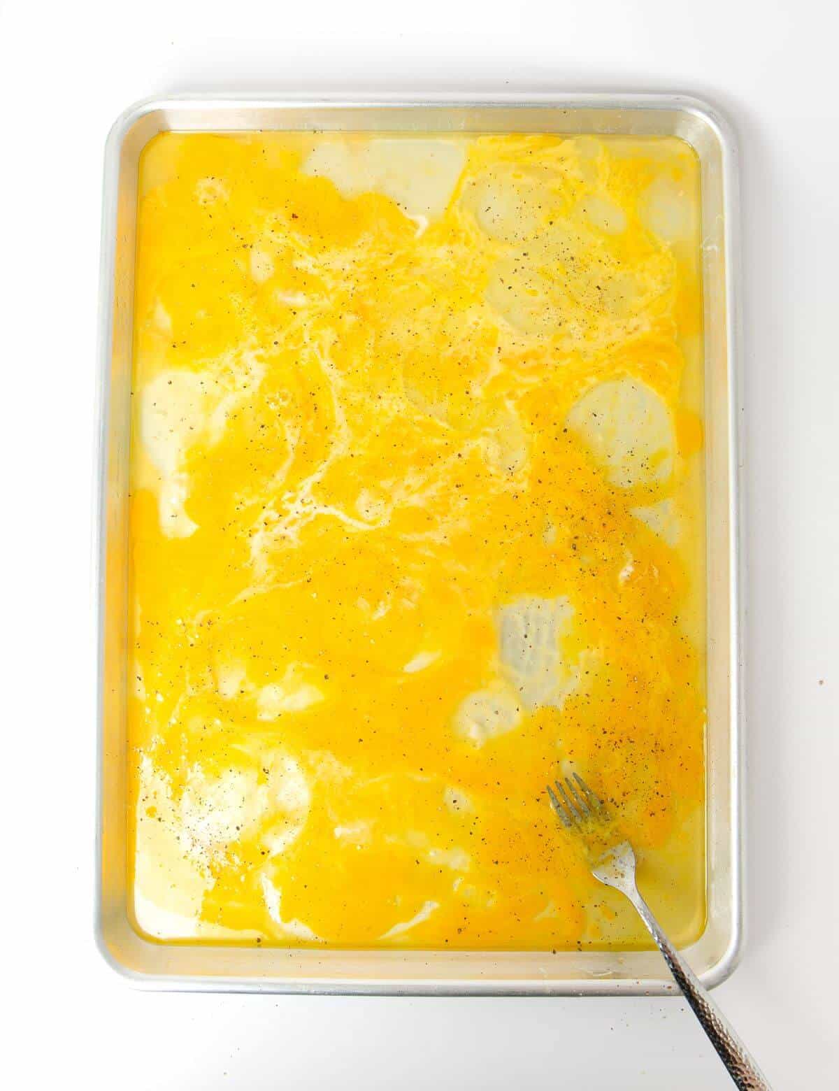 egg yolks and egg whites mixed together with fork on baking sheet