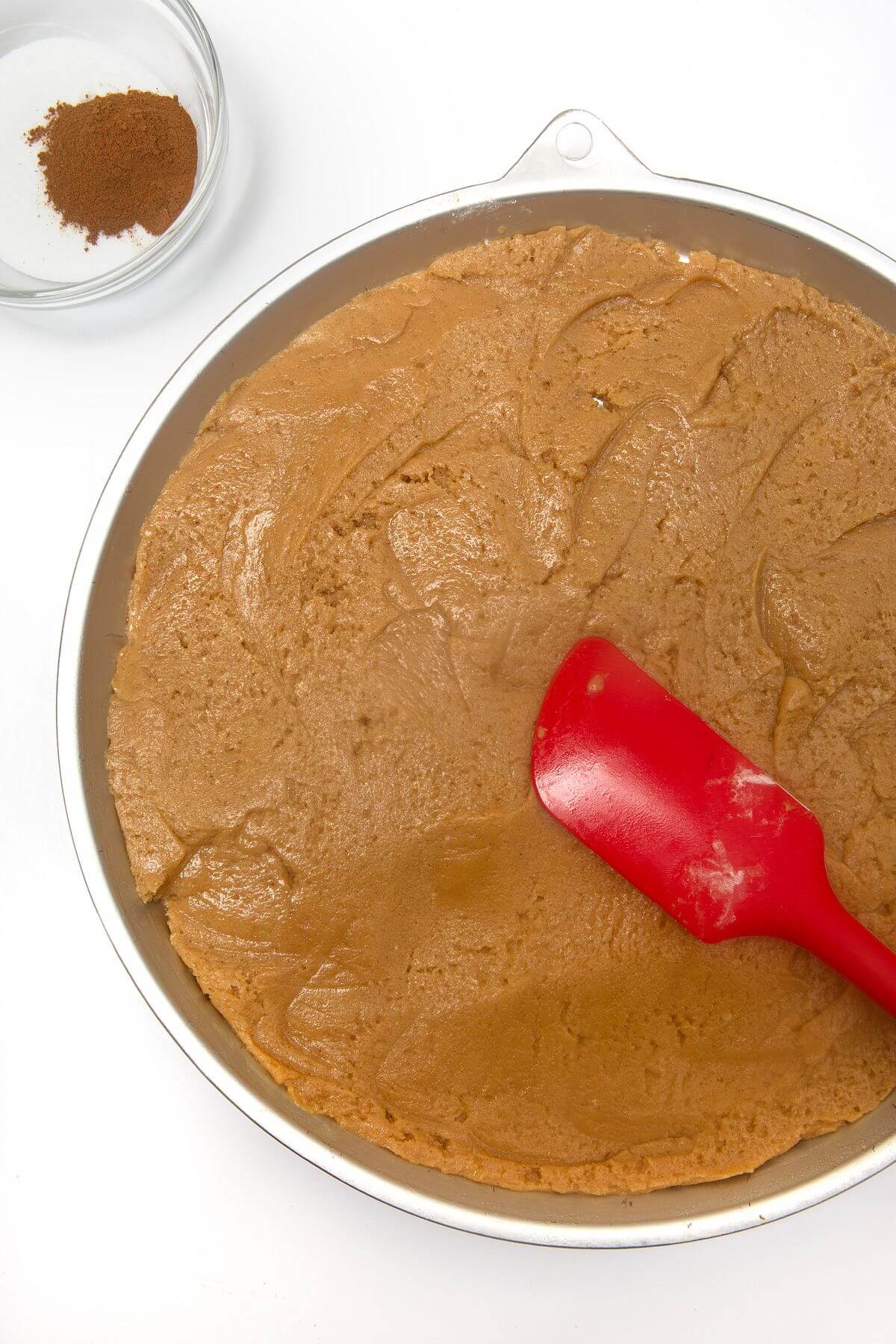 Snickerdoodle cookie cake dough spread evenly into cookie cake pan.