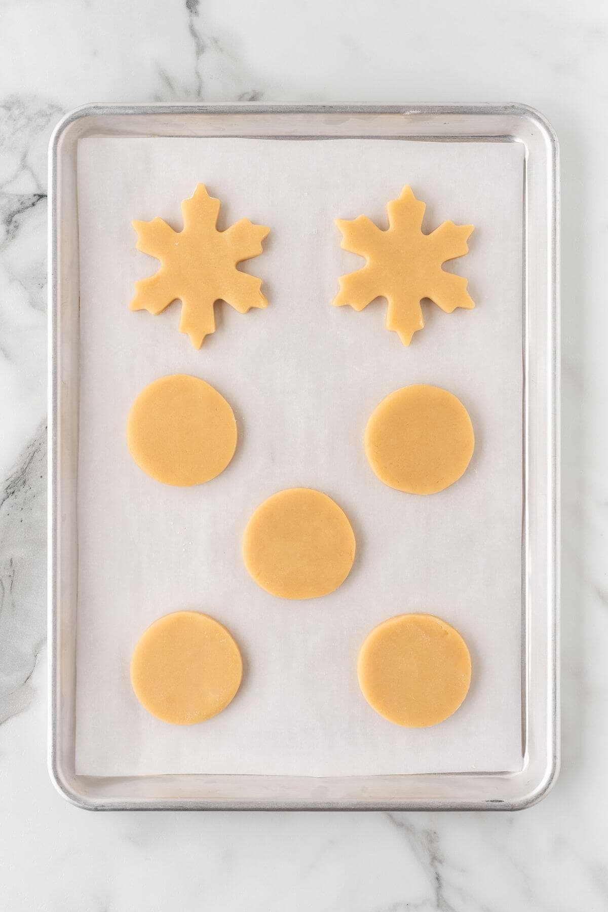 cut out sugar cookies on parchment-lined baking sheet