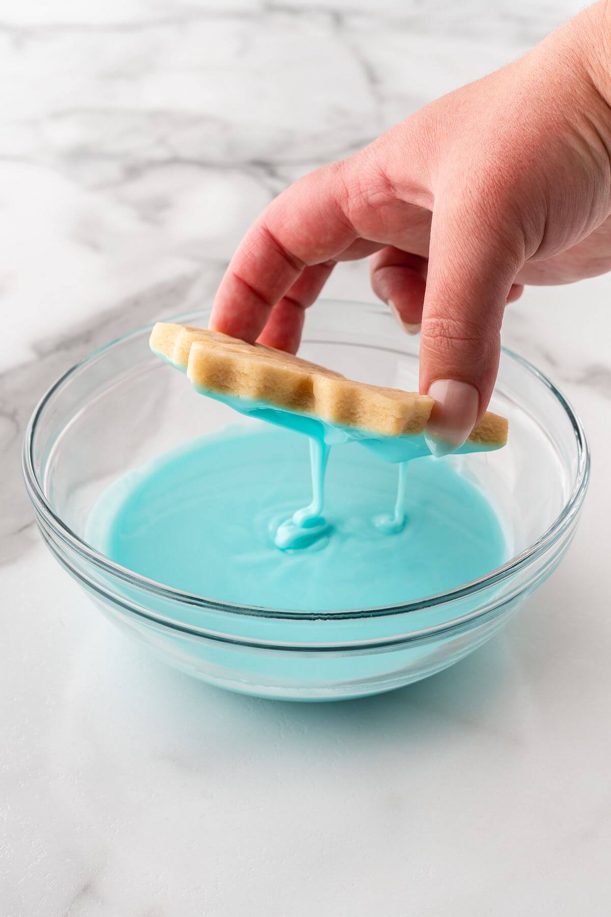 dipping snowflake sugar cookie in blue icing