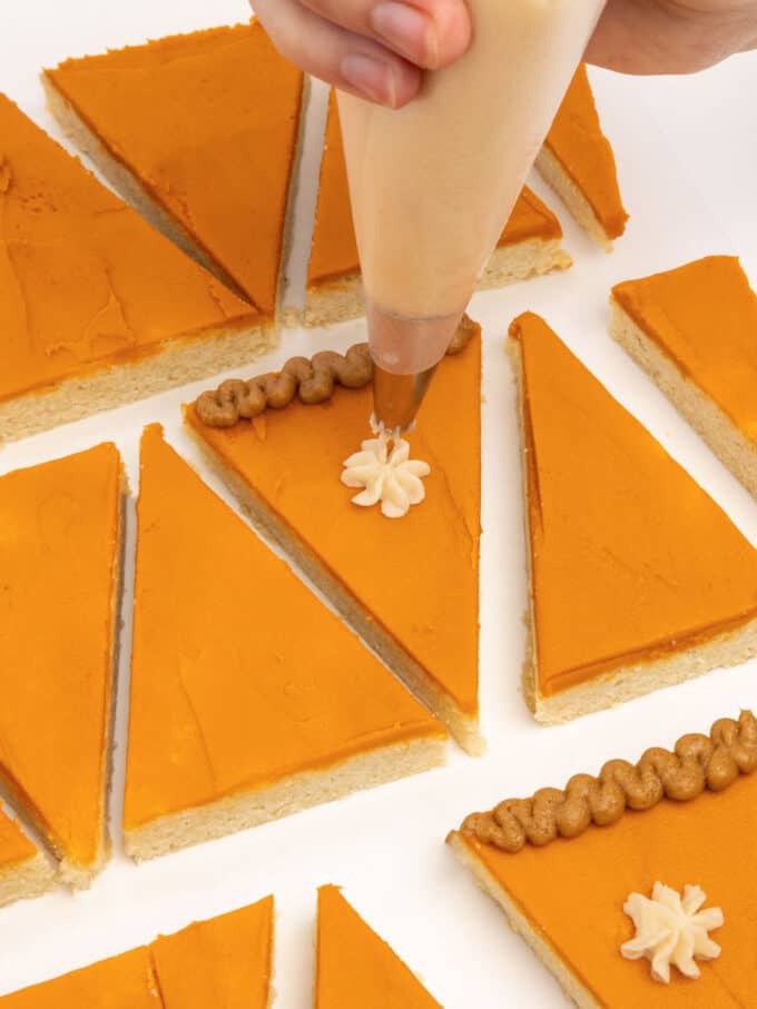 piping white whipped cream dollop on pumpkin pie slice sugar cookie bar